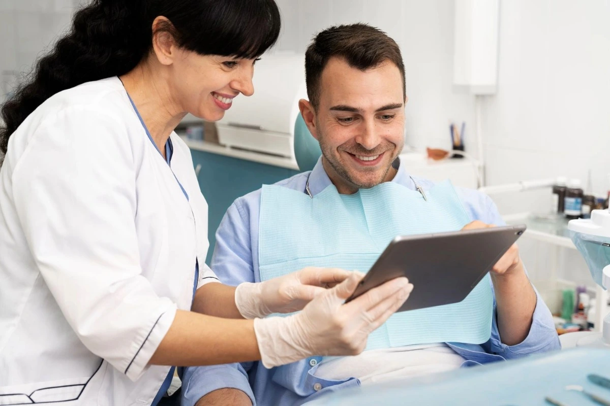 Dentist and patient smiling while reviewing information on a tablet