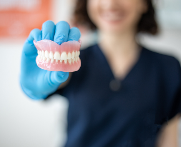 Gloved hands holding a full denture