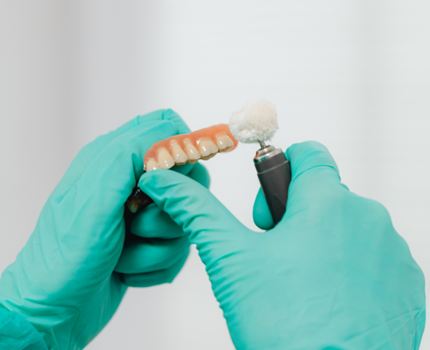 Gloved hands polishing a denture