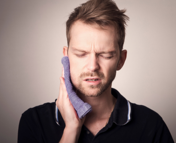 Man pressing a cold compress to his cheek from tooth pain
